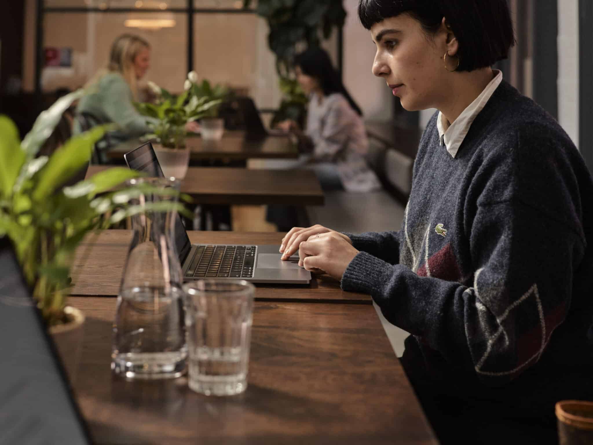 a woman sitting at a desk working on her laptop.