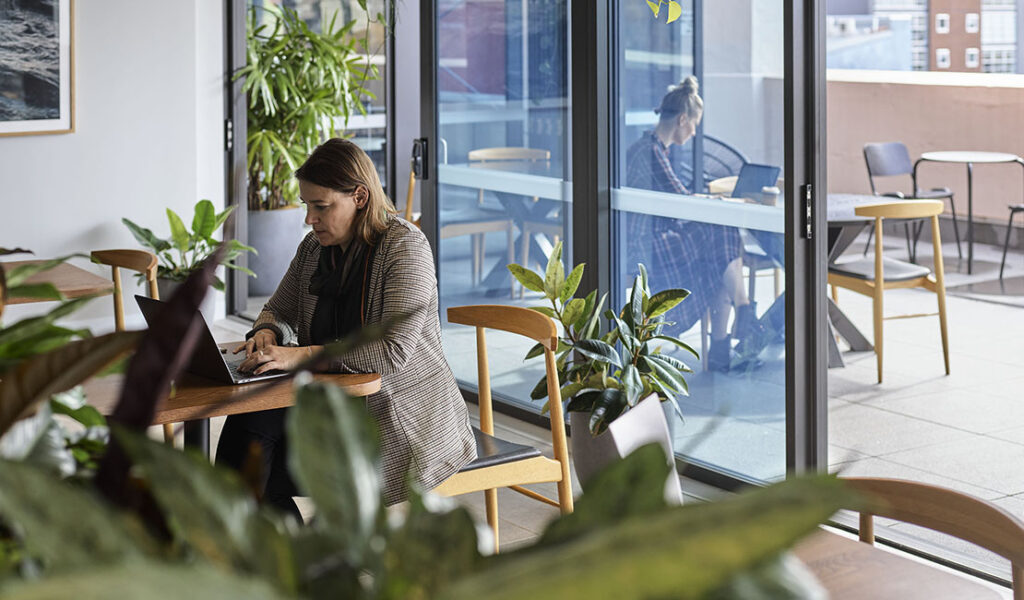 Woman sitting in carbon neutral coworking space surrounded by plants