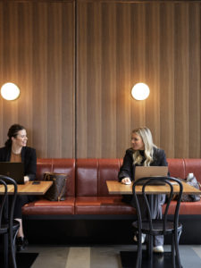 two women sitting in a cafe space chatting
