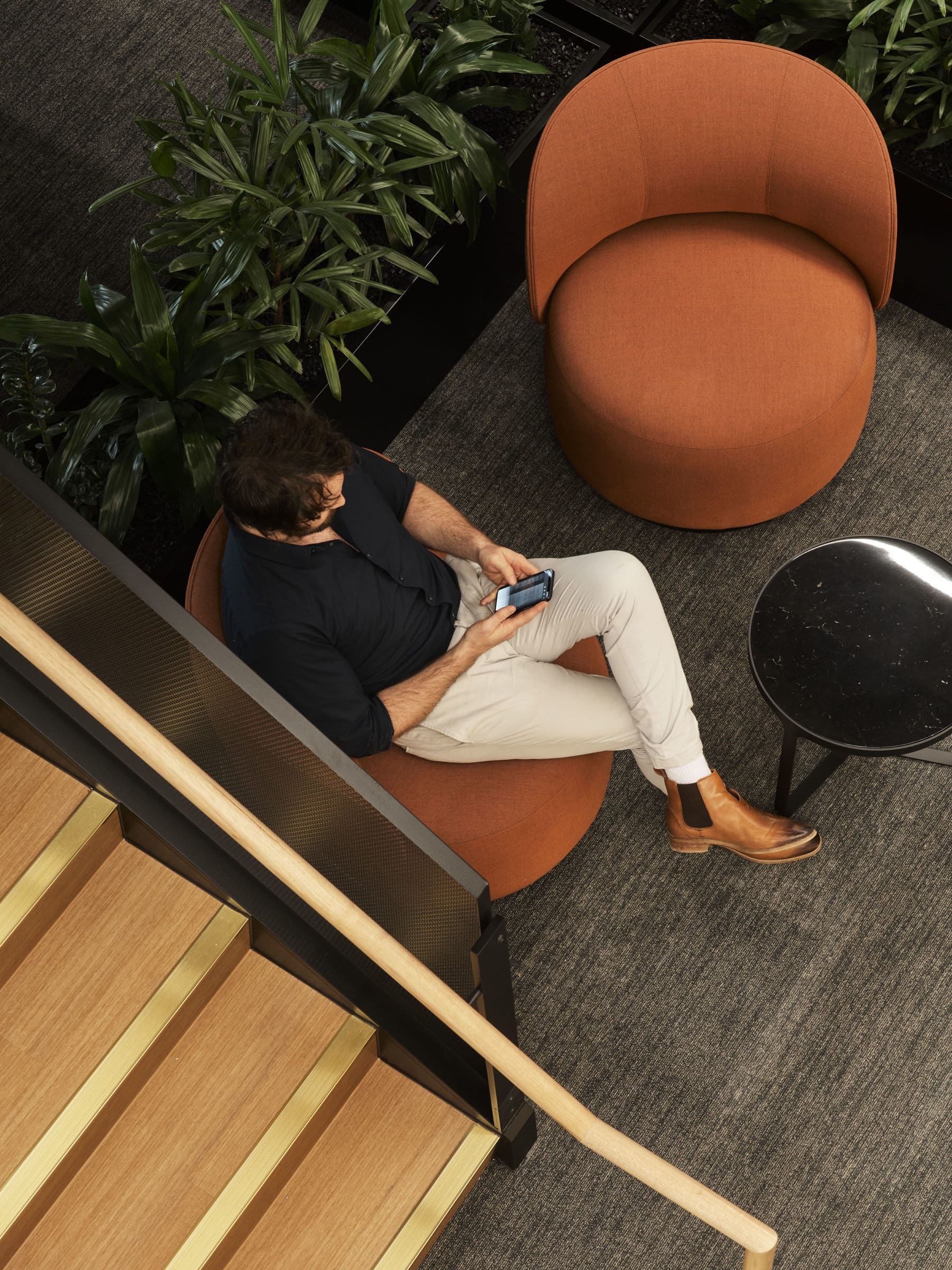 man sitting on orange couch texting on the phone