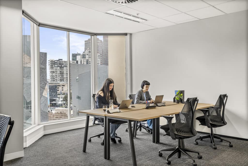 two women working in an office with a window behind