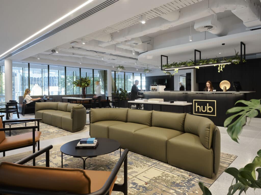 Hub Civic Quarter cafe and welcome area. Green couches and brown leather chairs with indoor plants.