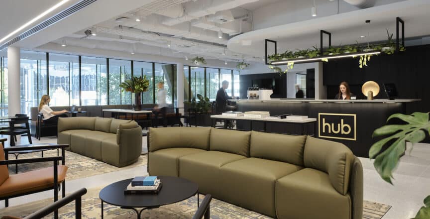 Hub Civic Quarter cafe and welcome area. Green couches and brown leather chairs with indoor plants.