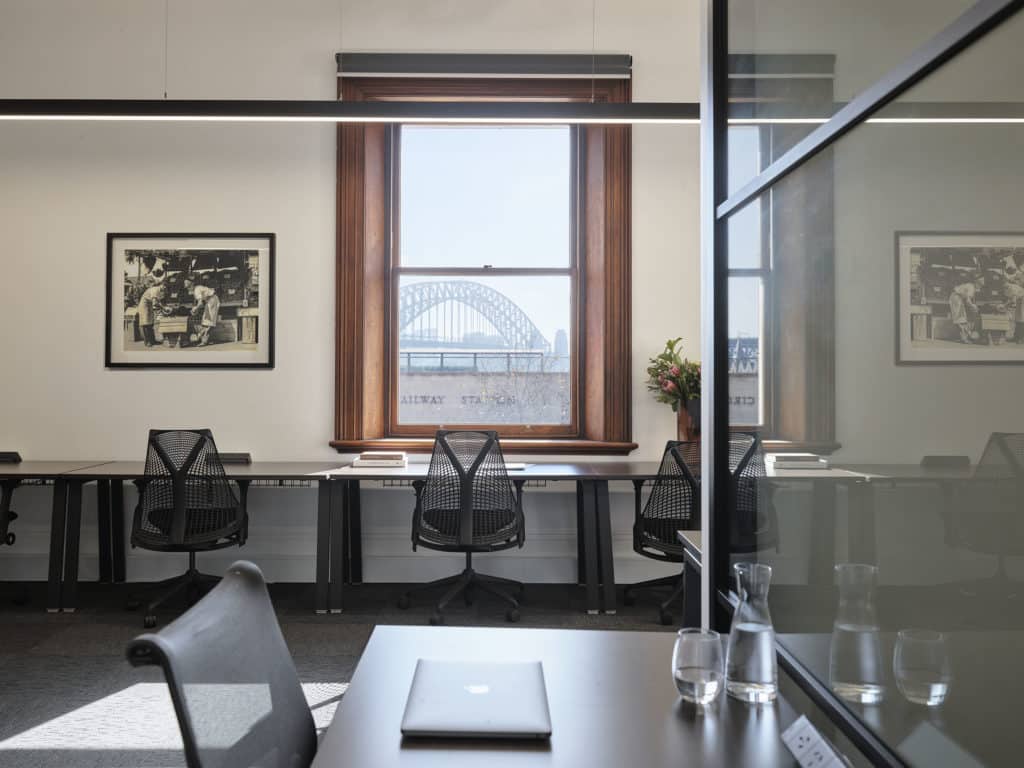 an office with desks and chairs, and a view of the Sydney Harbour Bridge