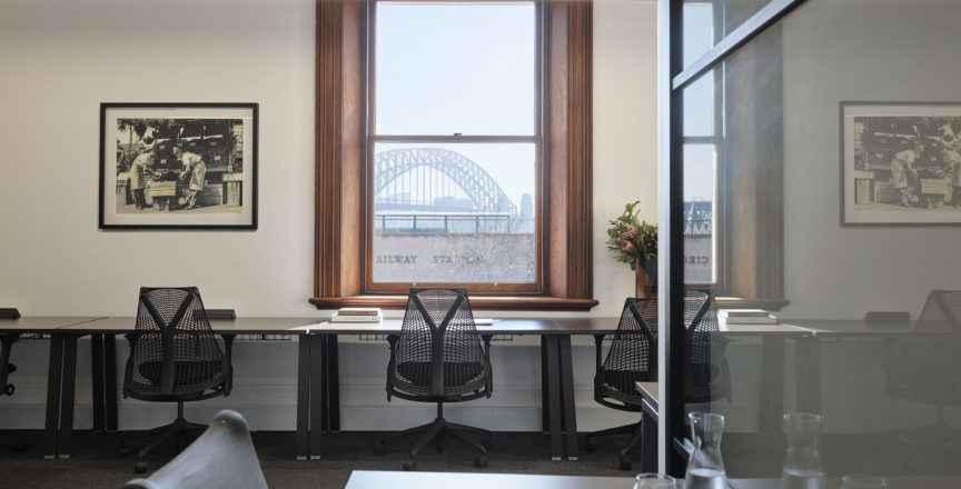 an office with desks and chairs, and a view of the Sydney Harbour Bridge