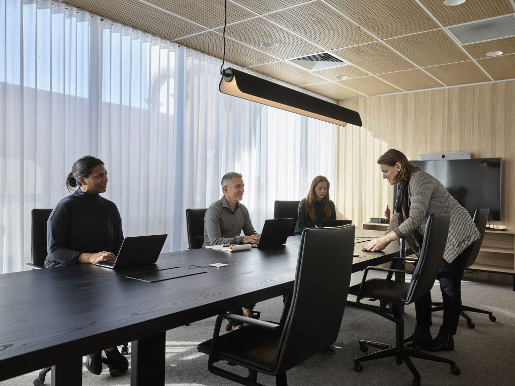 people in a board meeting with laptops open