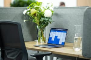 open laptop, jar of flowers, and water pitcher on desk