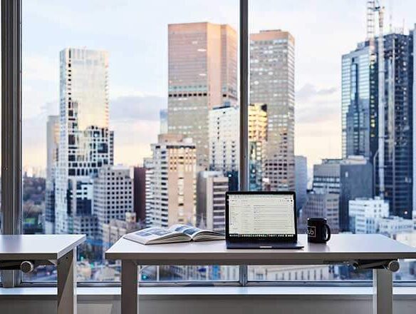 Laptop with a background view of Melbourne city skyline from Hub Parliament Station