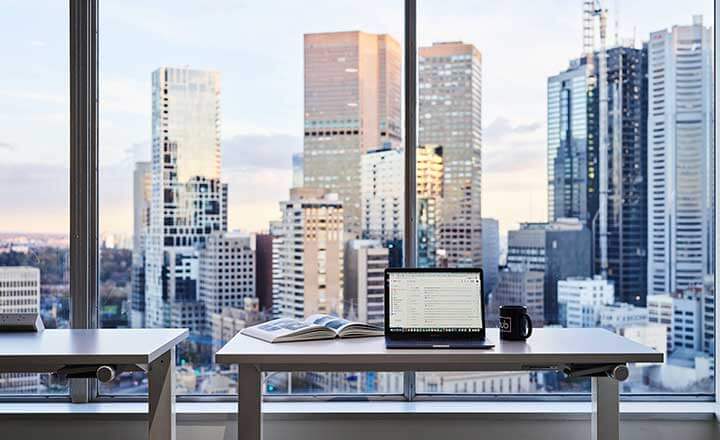 Laptop with a background view of Melbourne city skyline from Hub Parliament Station