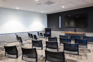 workshop training room with chairs facing a screen and microphone