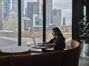 woman working on a laptop computer with a view of Flinders Street Station