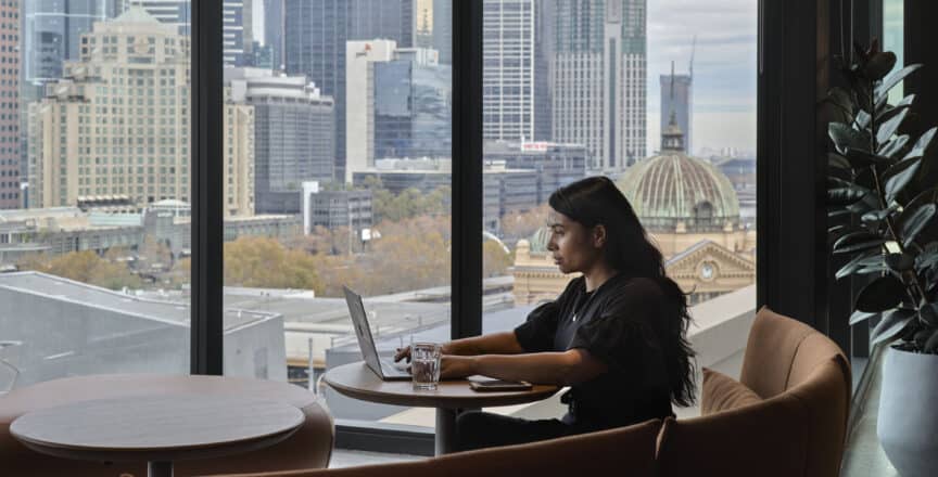 woman working on a laptop computer with a view of Flinders Street Station