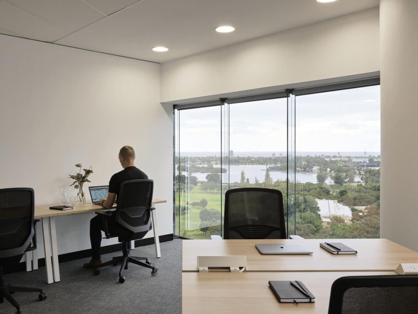 At Hub St Kilda Road a man working alone in office with a view of Albert Park Lake