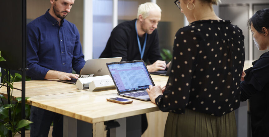 people in an office working at standing desks