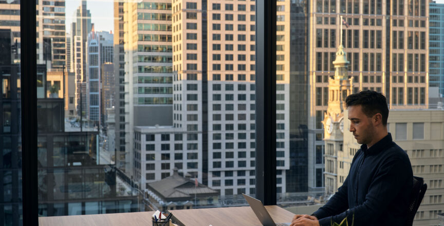 man working at a desk with view of the city