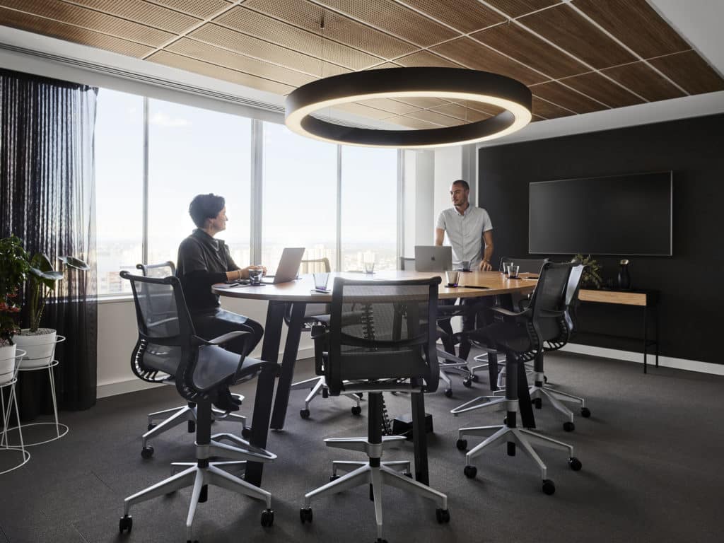 man and woman in meeting room with view of city