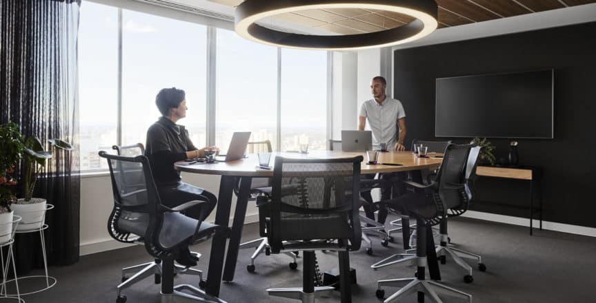 man and woman in meeting room with view of city