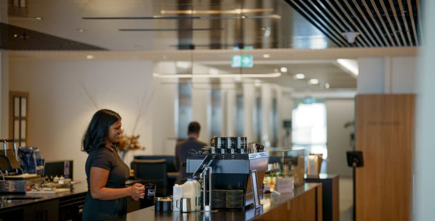 woman smiling at counter serving coffee