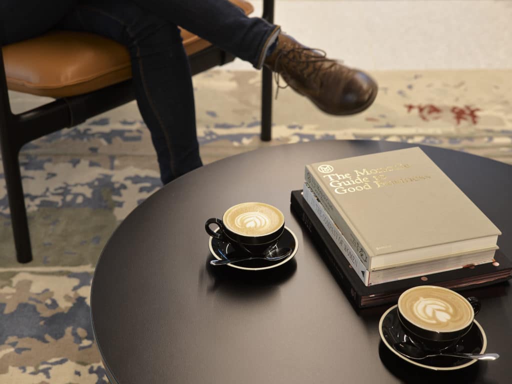 a person sitting at a table with two coffees and a book