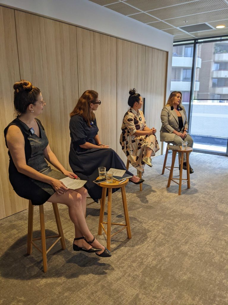 Four speakers on stools at a panel event