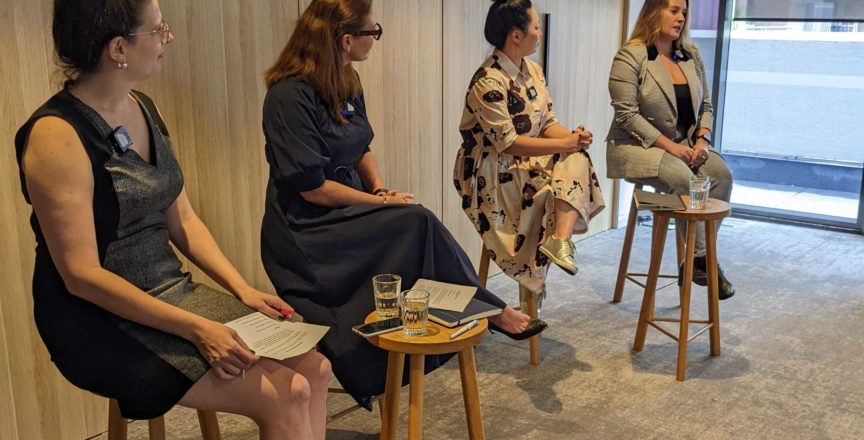 Four speakers on stools at a panel event