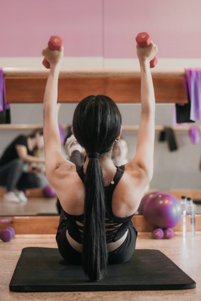woman holding weights in a barre class
