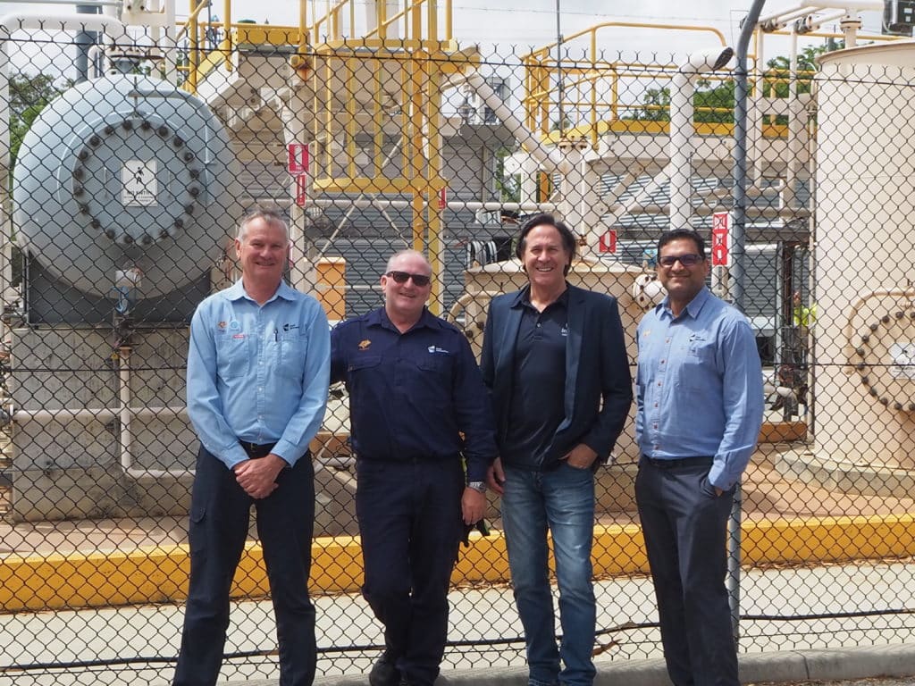 Four workers standing in front of a power plant