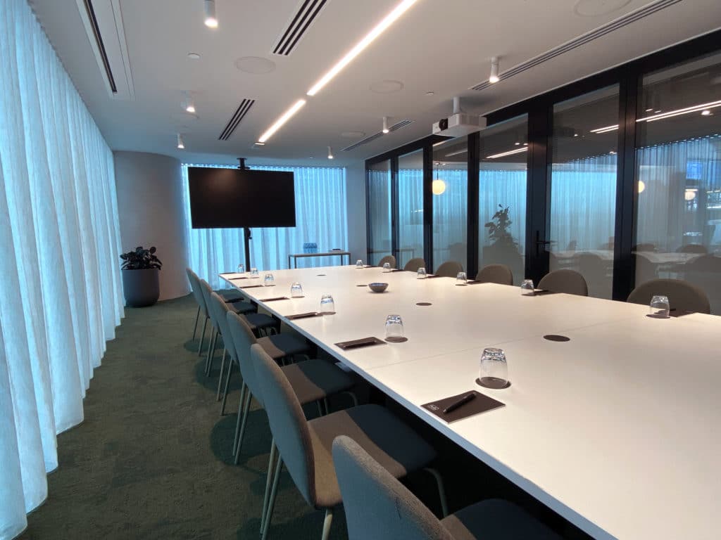 meeting room with long white table, chairs and screen