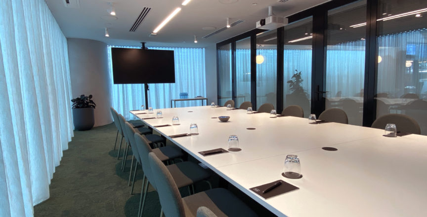 meeting room with long white table, chairs and screen