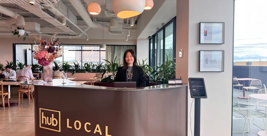 woman smiling behind a desk that says Hub Local