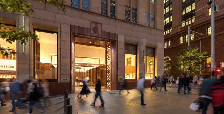 An image of the Rolex Boutique in Martin Place. The lights are on and there are people walking around outside.