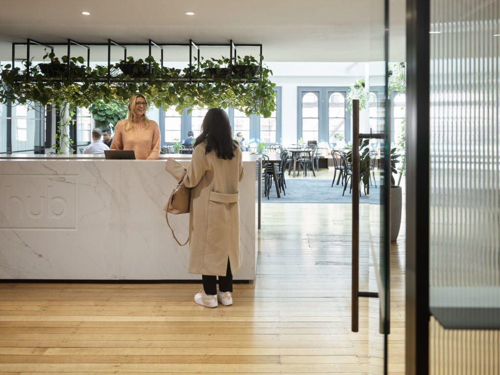 a person standing at a white concierge desk, speaking to the concierge