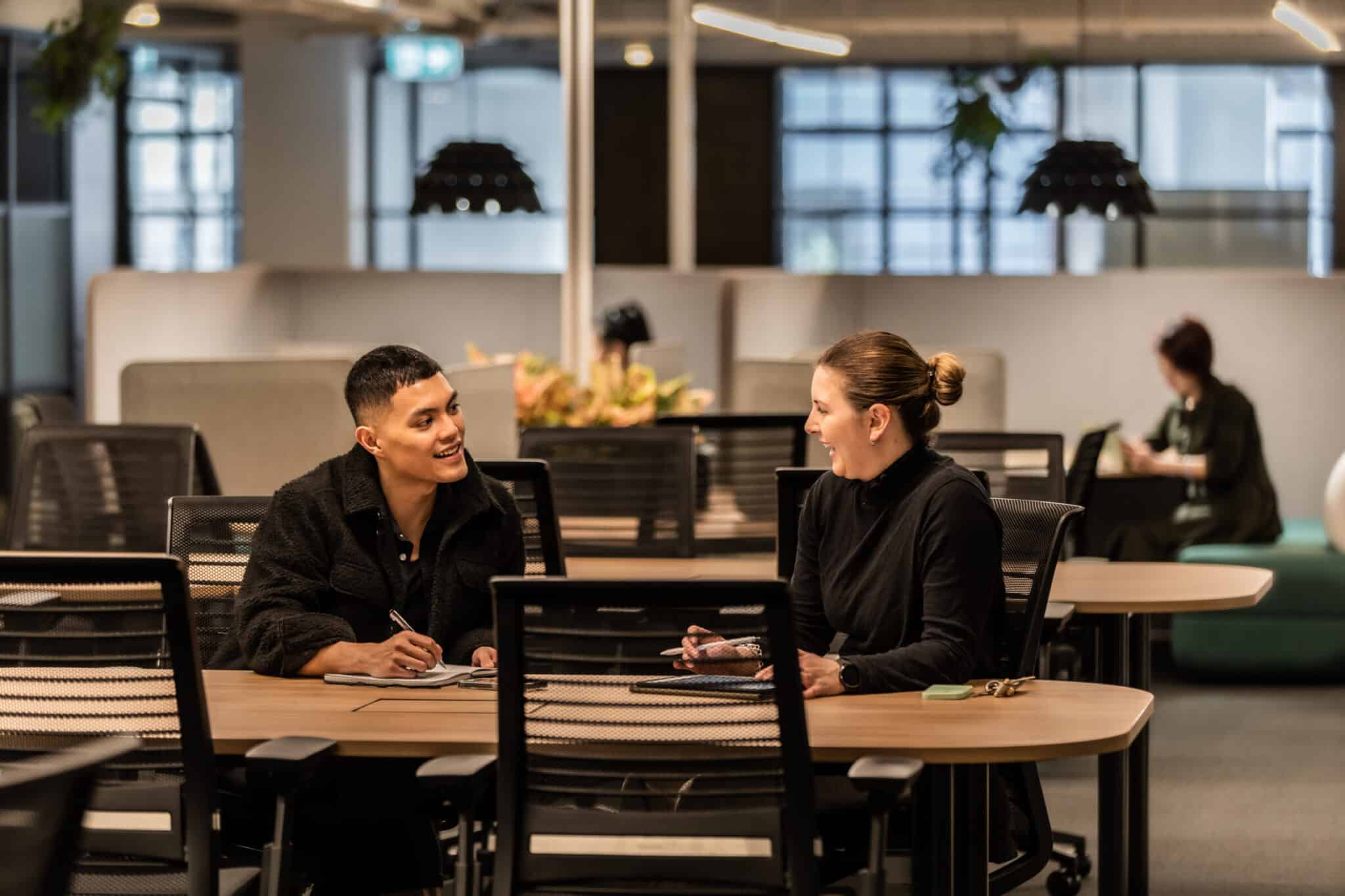 Two people looking at eachother smiling at work