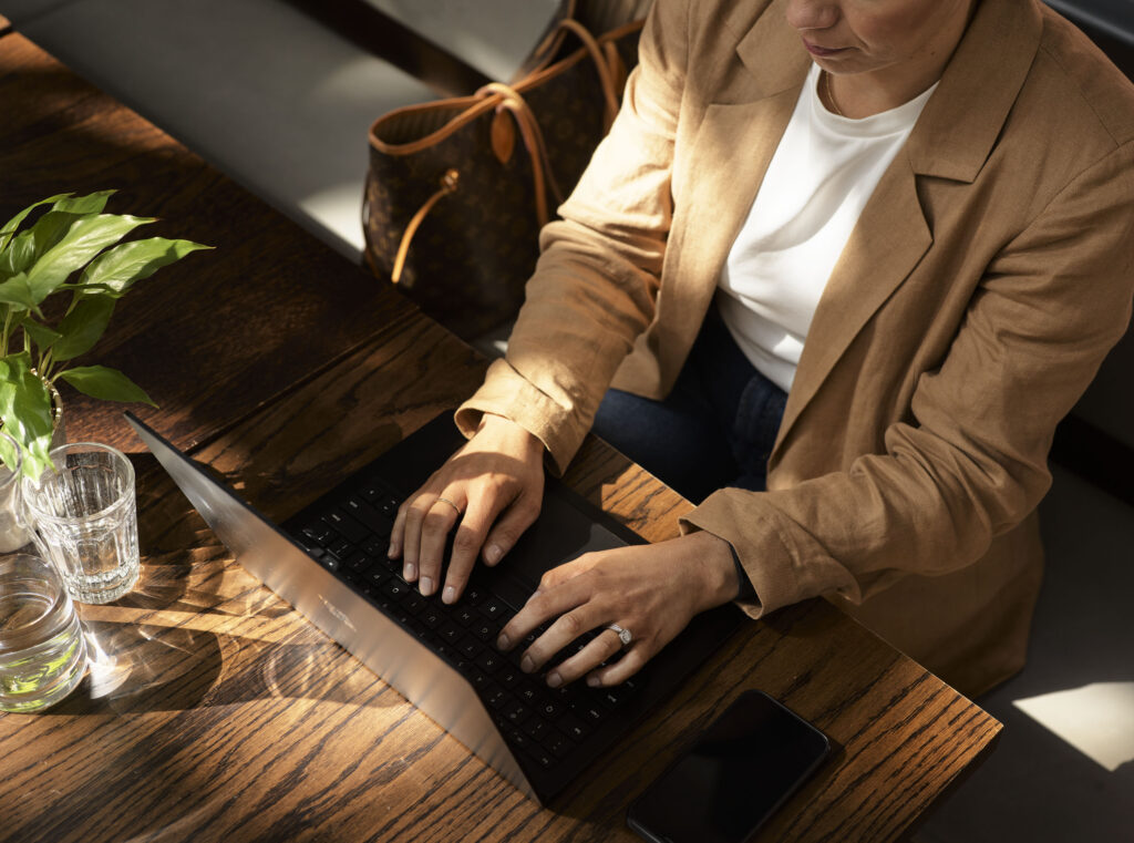 a woman in a brown blazer sitting at a table with their laptop open