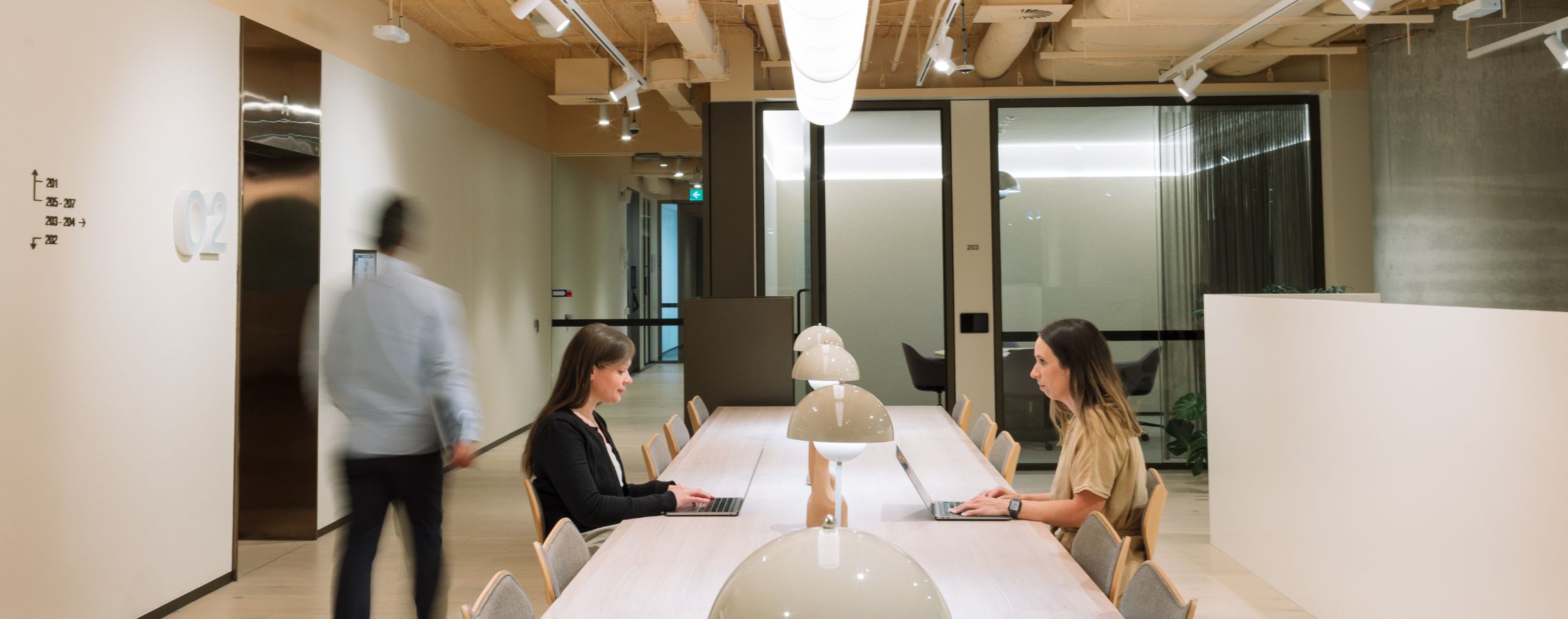 Two women collaborating on laptops in a Hub workspace, driving modern business growth through professional networking.