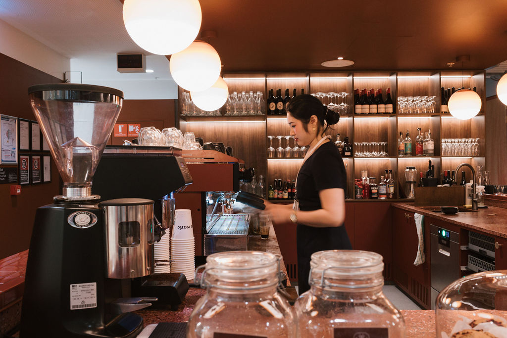A hospitality lead prepares coffee behind a high-end café counter at Hub Martin Place.